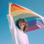 A young lady holding a rainbow flag.