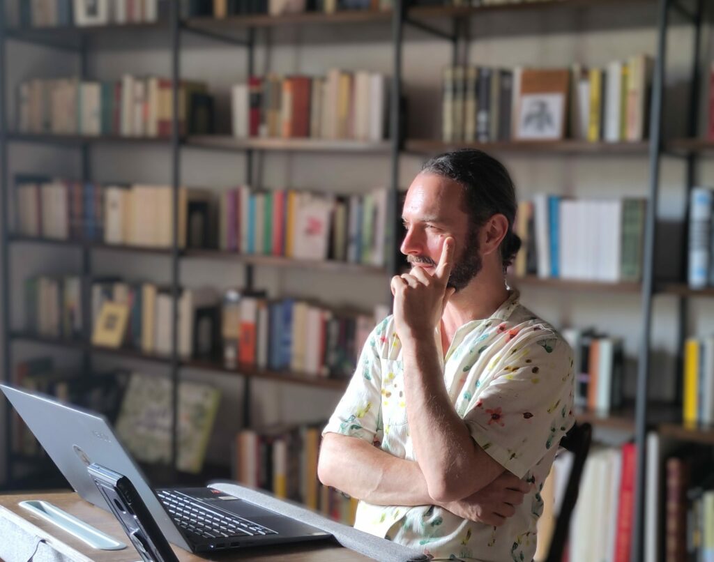 A young man in his study, in front of a pc.